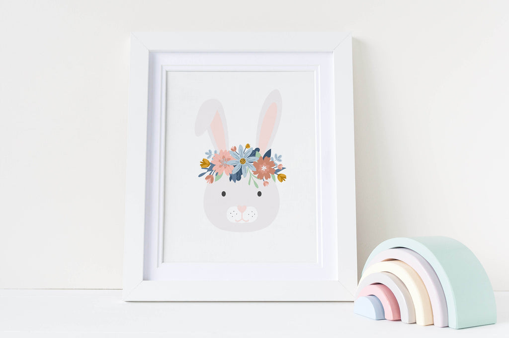 A Wall Funk Nursery Art Print featuring a bunny with a flower crown next to pastel wooden rainbows on a white nursery shelf.