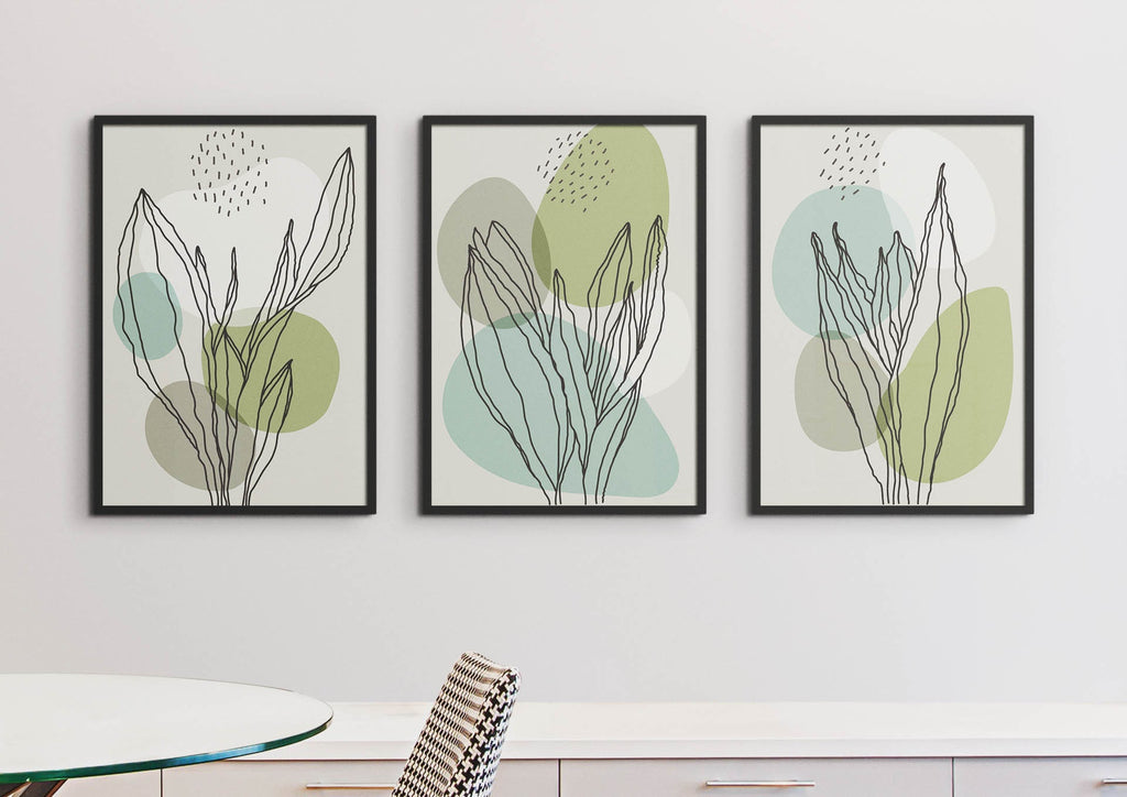 Three "Delicate Green Leaves" floral prints by Wall Funk with green & blue accents hang above a cabinet. Custom sizes available.