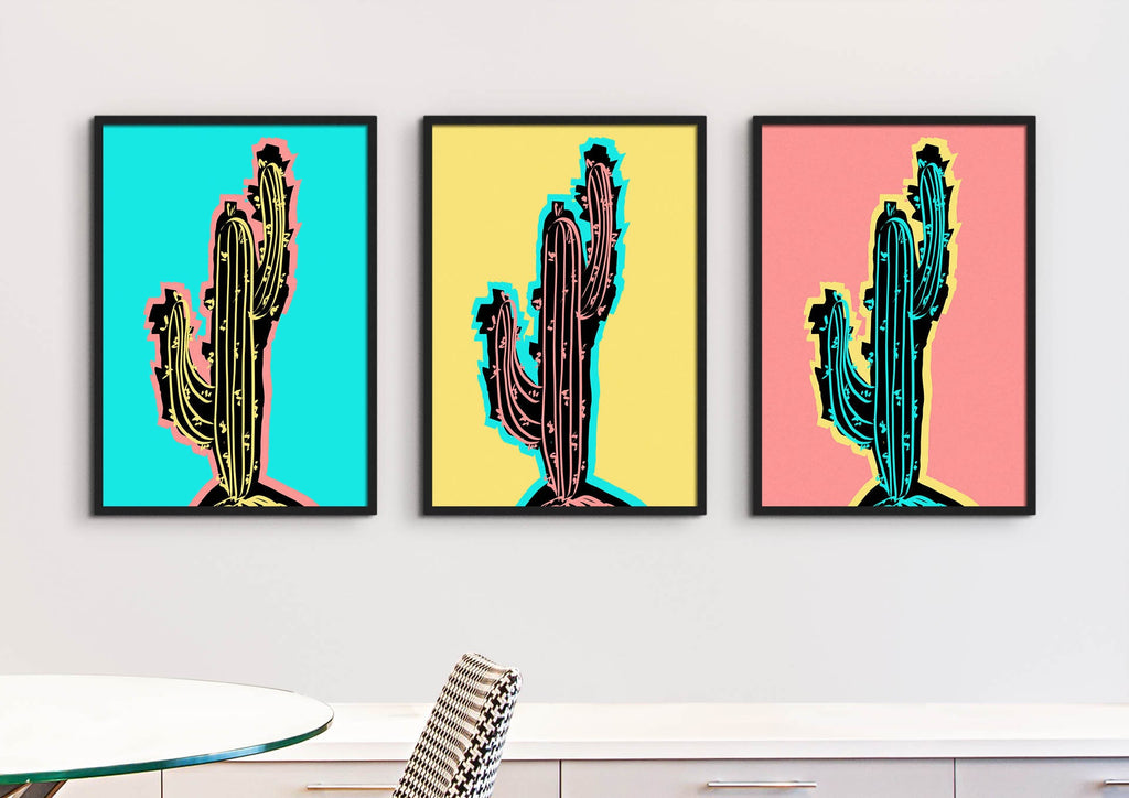 The "Vibrant Pop Art Cactus Wall Art Prints" by Wall Funk hang on a white wall, featuring vibrant blue, yellow, and pink backgrounds.