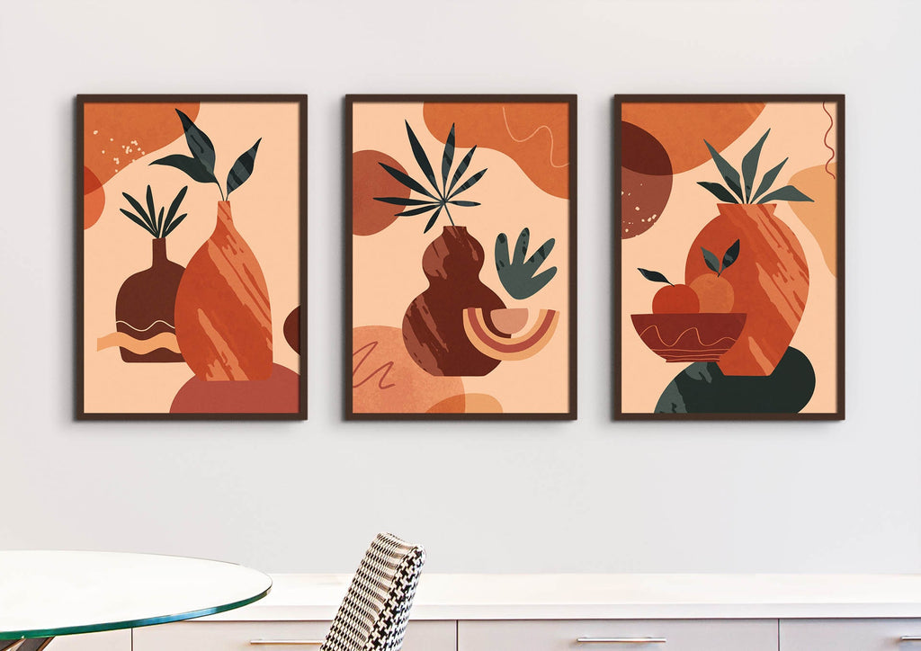 Three "Floral Abstract Wall Art" pieces by Wall Funk showcase plants and fruits above a white table and chair in earthy tones.