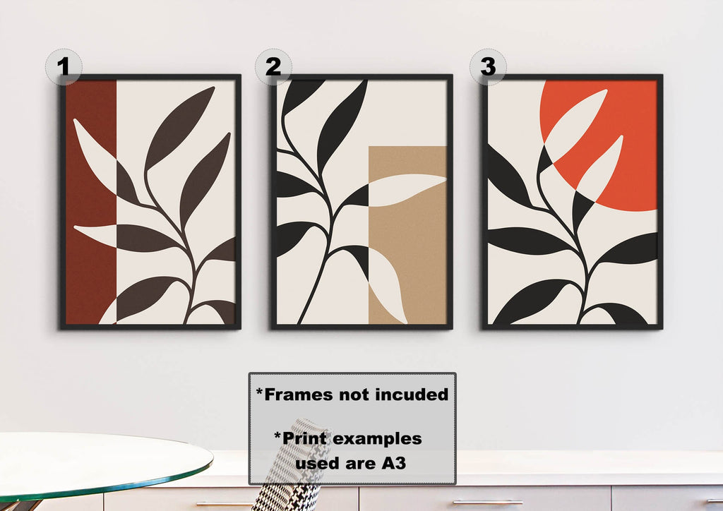 Three framed Floral Abstract Wall Art prints by Wall Funk, with bold shapes and colors, adorn the wall above a table.