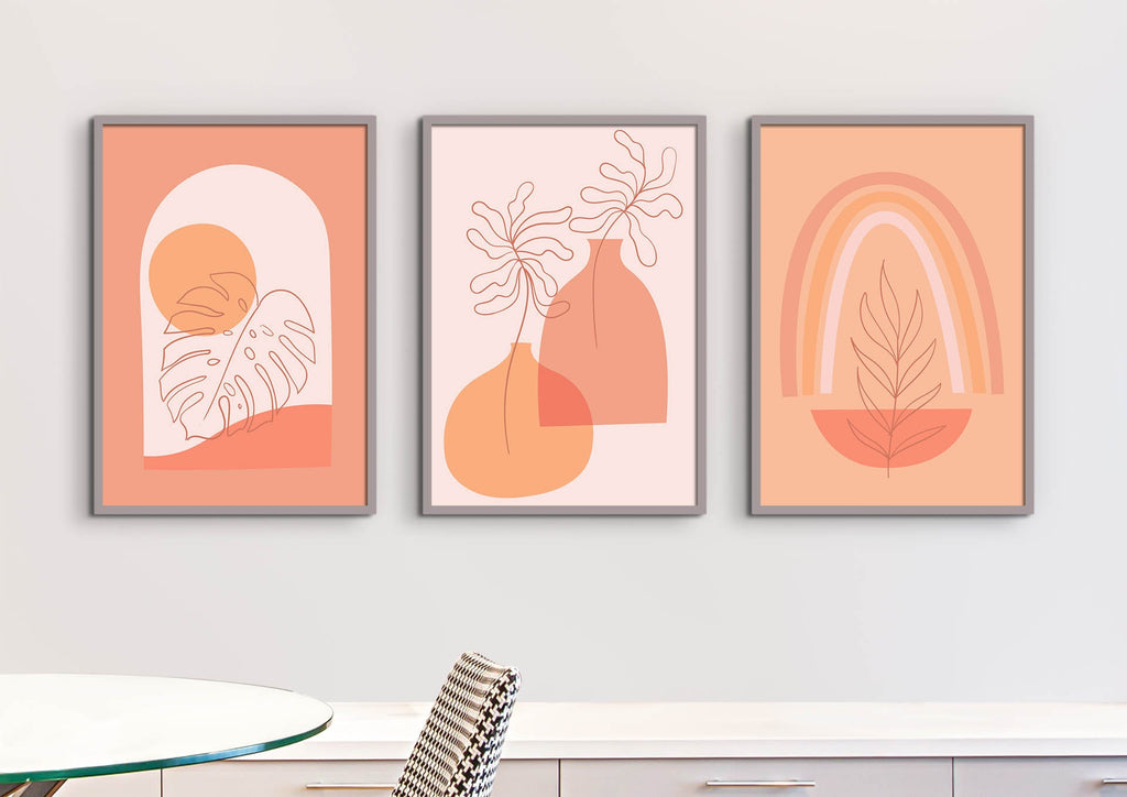 Three 'Floral Abstract Wall Art' pieces from Wall Funk, in orange and beige, hang on a white wall above a table.