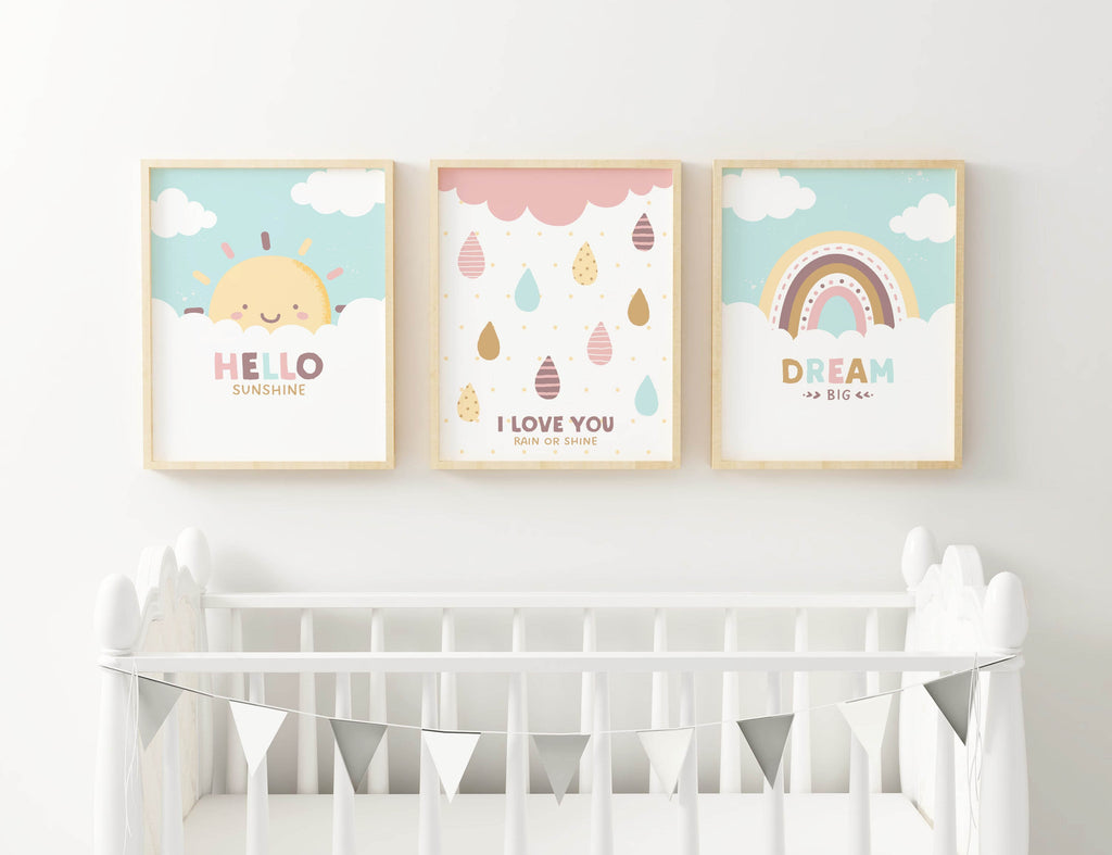 Above a white crib hang three Wall Funk framed nursery prints: a smiling sun, raindrops with "I love you," and a vibrant rainbow.