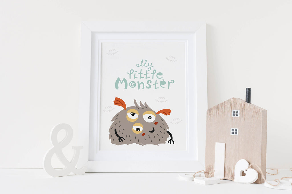 A framed Wall Funk print of a cute furry monster with "My Little Monster," next to a wooden house and ampersand decoration.