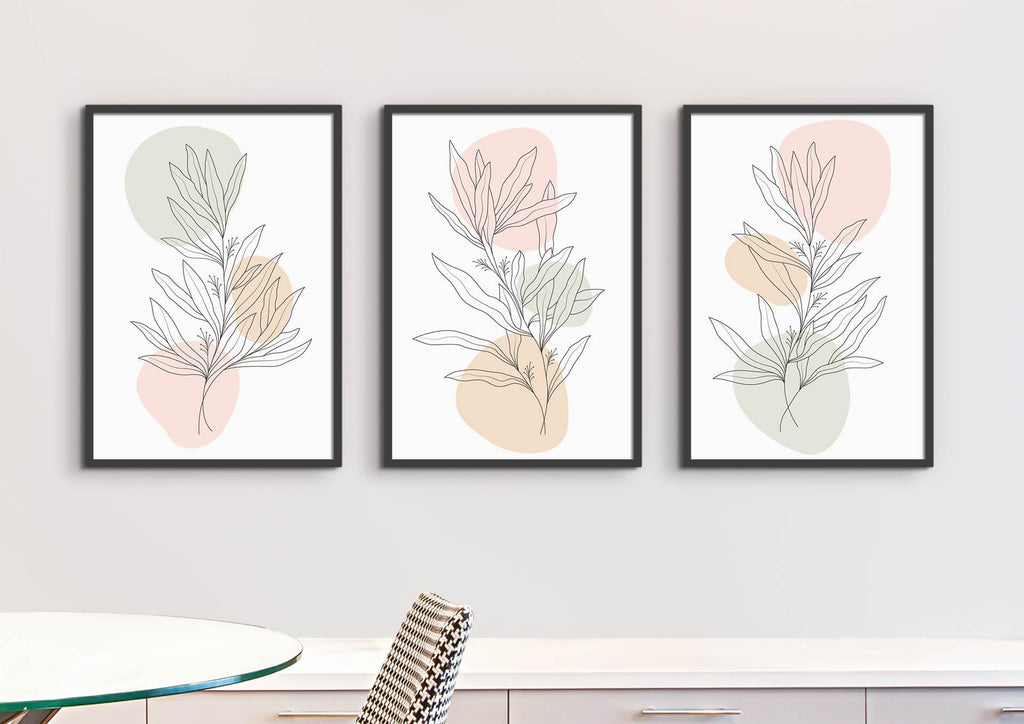 Three Frames of Wall Funk's Floral Abstract Wall Art grace a white wall above a table, featuring pastel green, pink & beige backgrounds.