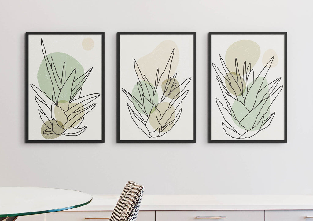 Three Wall Funk Minimalist Green Boho Leaves Floral Abstract Wall Art Prints on a white wall above a sideboard, near a glass table with a chair.