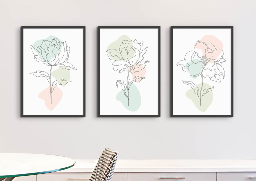 Three "Floral Abstract" prints by Wall Funk add elegance above a table and chair with their minimalist floral designs on pastel backgrounds.